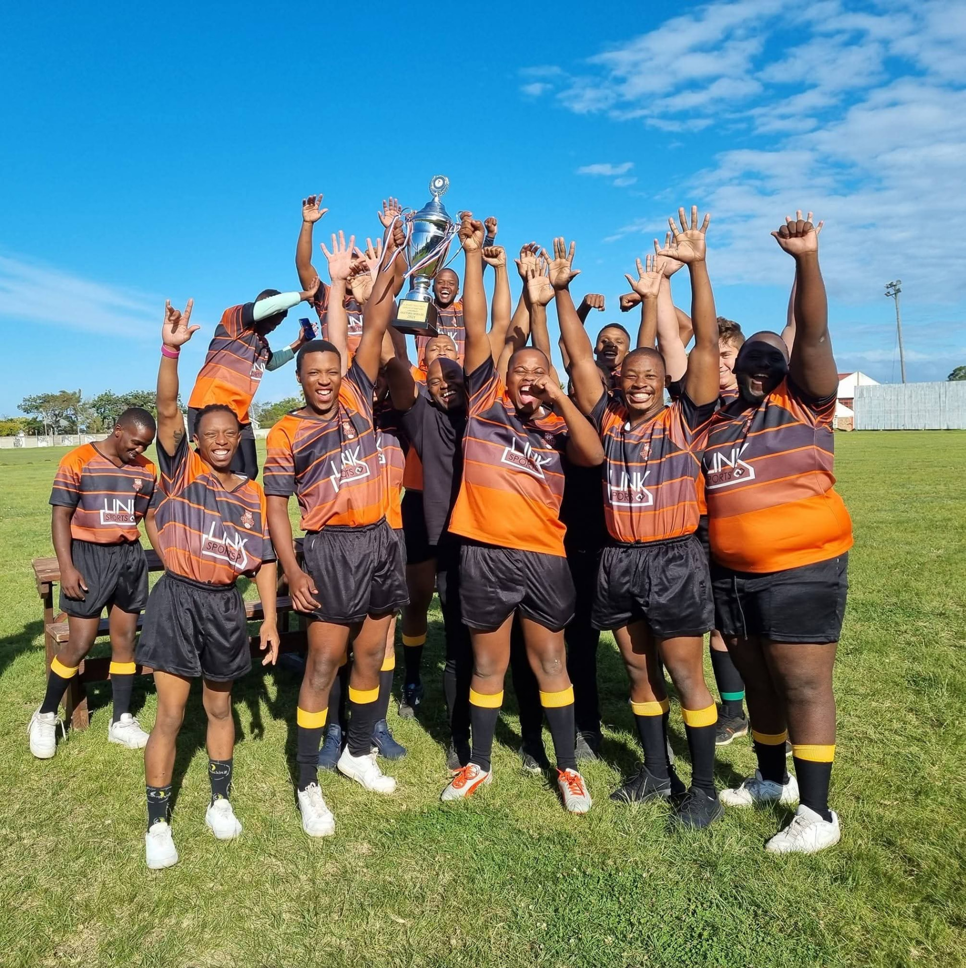 Olutsha Wolves players celebrating on the field with a championship trophy raised