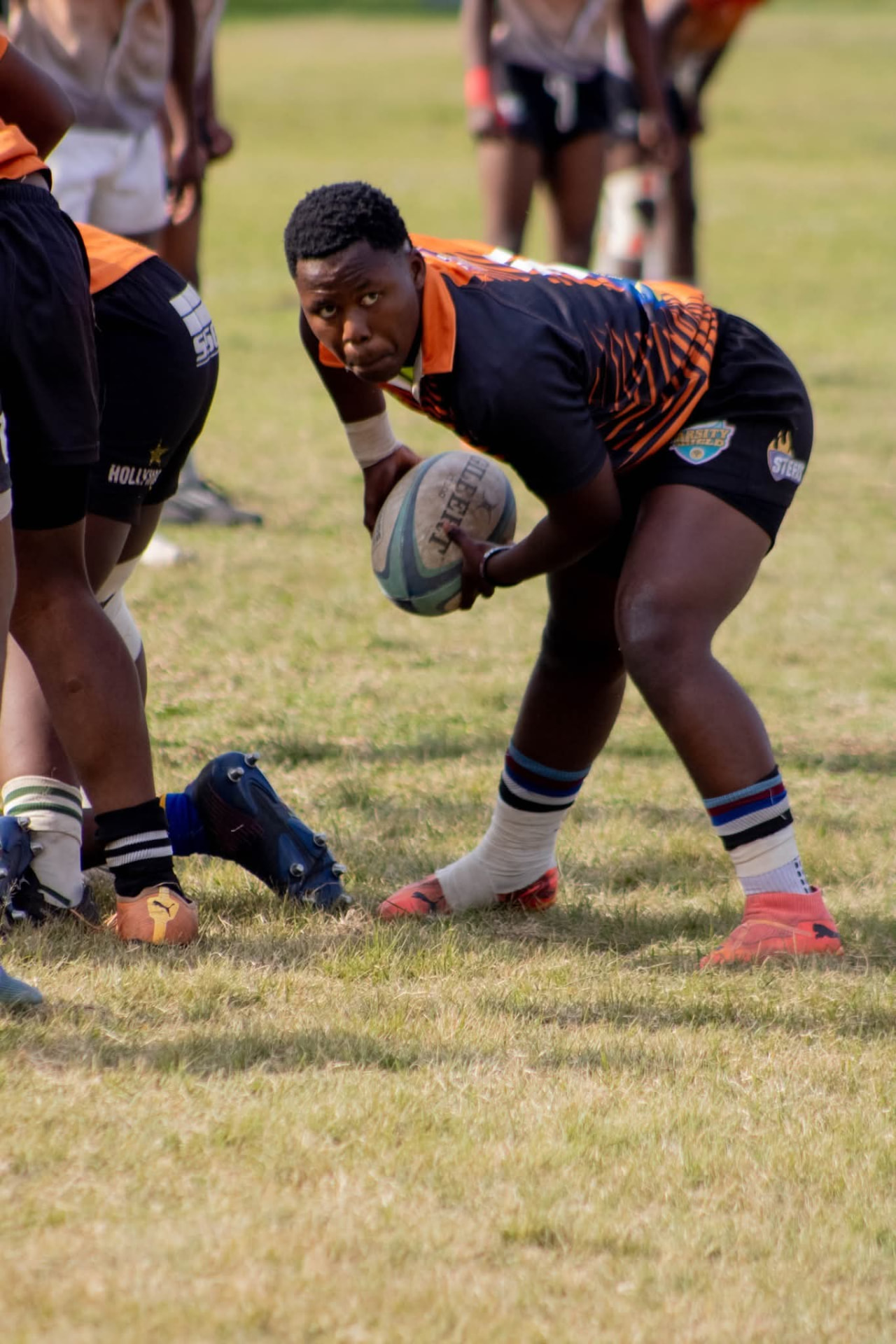 Olutsha scrumhalf in black and orange preparing to pass from the base