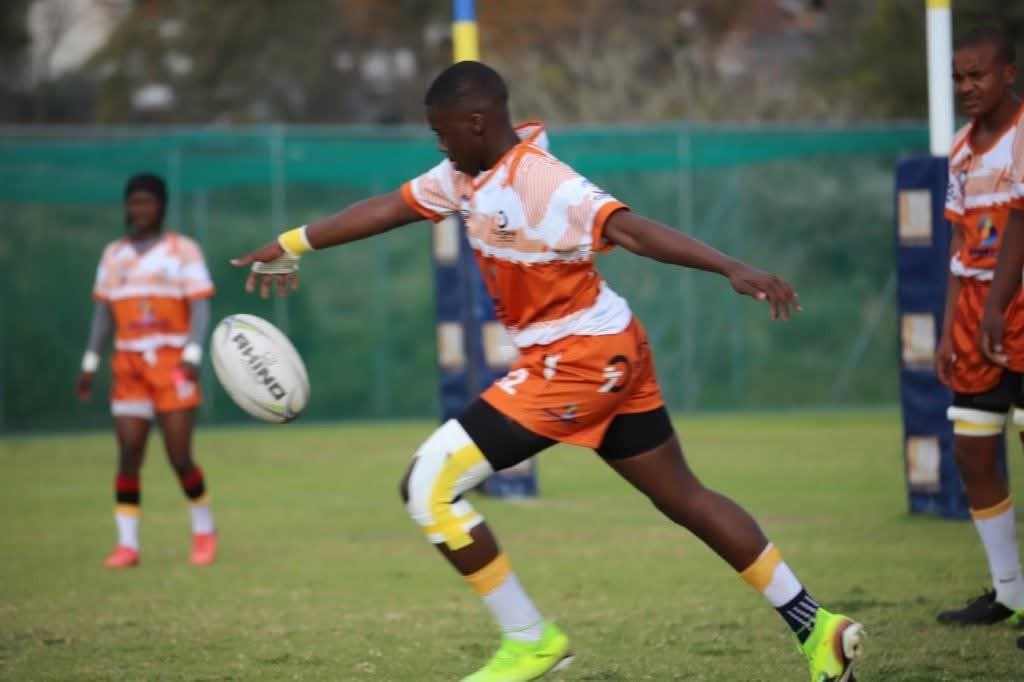 Olutsha player in orange kicking the ball during a match